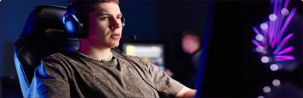Een geconcentreerde esports-speler met een headset op, zittend achter een gaming-pc, volledig opgaan in het spel met kleurrijke verlichting op de achtergrond